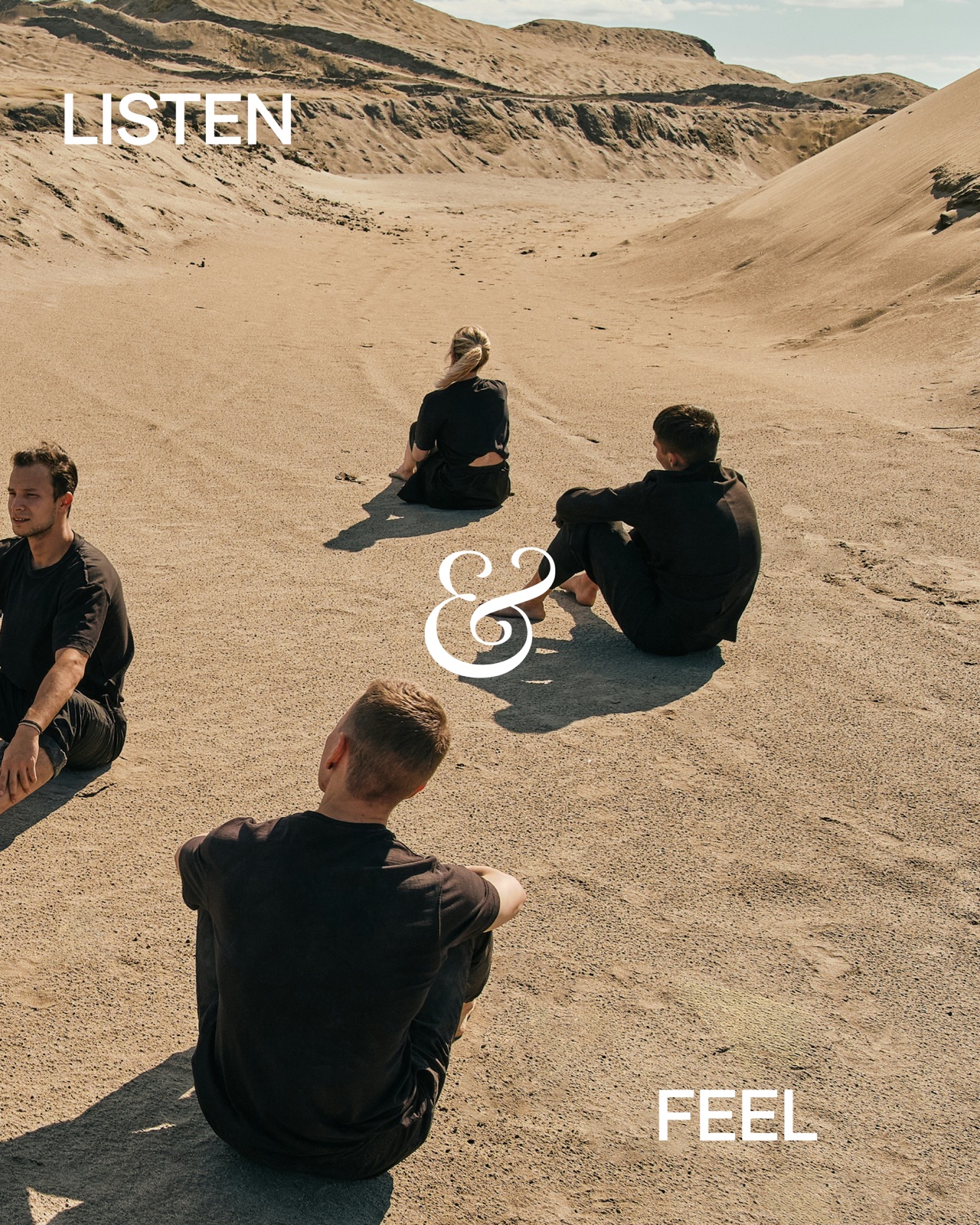 Group sitting on the sand, facing into a circle.
